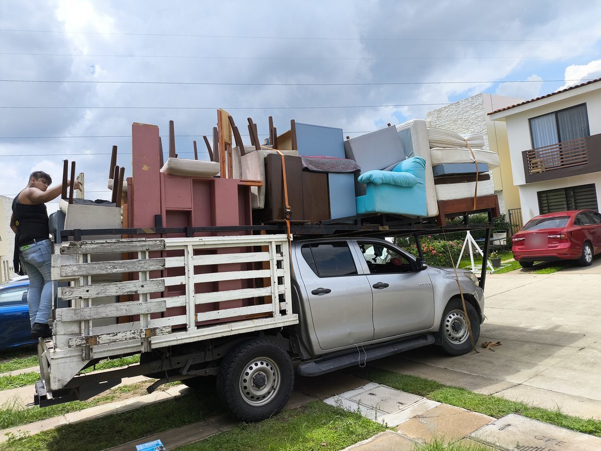 Hilux con mudanza completa y un trabajador acomodando la carga